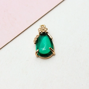 Detailed view of a green teardrop crystal pendant with gold flower accents and metal trim