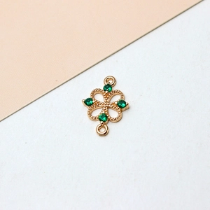 Macro detail of gold-plated clover charm with green zircons and dual connecting loops