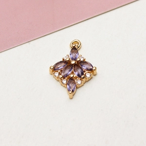 Macro shot of gold-plated flower pendant with marquise purple zircon and small diamonds