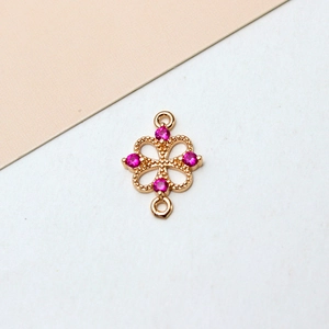 Macro view of gold-plated clover jewelry connector with pink cubic zirconia stones