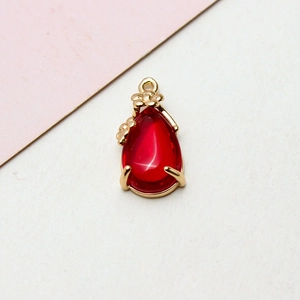 Detail of red teardrop pendant with gold floral edge and crystal-like texture