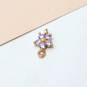 Macro shot of gold-plated flower pendant featuring purple zircons and dual-loop design