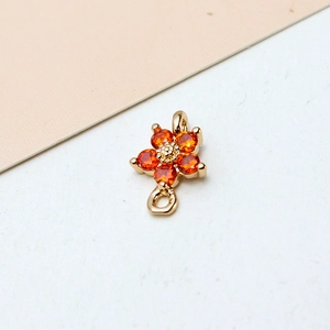 Macro shot of gold-plated five-petal flower pendant with orange stones and dual loops