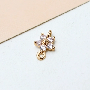 Macro shot of gold-plated flower pendant with clear cubic zirconia and double loops
