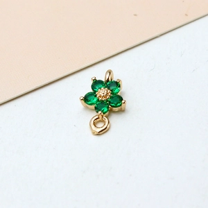 Macro shot of gold-plated flower charm with double loops and five green zircons