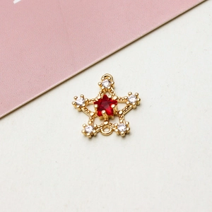 Dettaglio macro del ciondolo a stella con pietra rossa centrale e accenti di zircone bianco