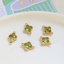 Detail van vijf groene kristallen klaverhangers met goudkleurige rand en dubbele ring