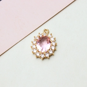 Macro shot of pink oval crystal pendant with zircon sunflower halo and golden clasp