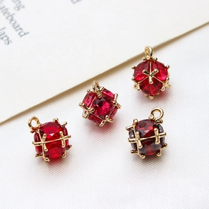 Macro shot of 4 red zircon cube pendants with gold plated cages for DIY jewelry making