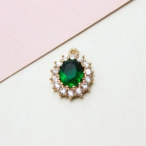 Macro view of emerald green oval pendant with white zircon halo and gold plating