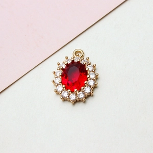 Close-up of an oval red gemstone pendant with white zircon cluster setting in gold