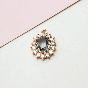 Macro shot of oval dark grey zircon pendant with white crystal halo on gold setting