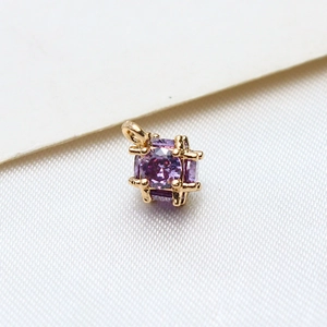 Macro shot of cubic gold-plated pendant with sparkling purple zircon gemstones