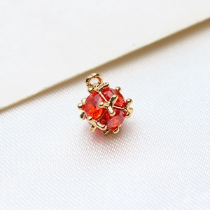 Macro shot of gold-plated sphere pendant with orange-red cubic zirconia for DIY jewelry