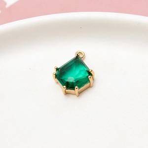 Close-up of an emerald green shield-shaped gemstone pendant with a gold metal frame