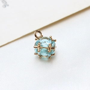 Macro detail of a light blue zircon cube pendant with 18k gold plated claw setting