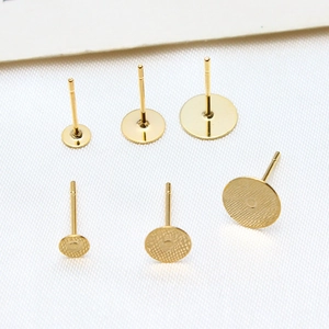 Detail of gold-plated flat pad earring posts in three sizes with smooth and mesh textures
