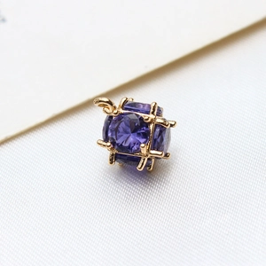 Macro shot of purple faceted zircon cube pendant with gold frame for DIY jewelry