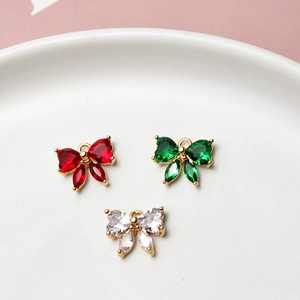 Three zircon bow pendants in gold plating, colors red, emerald green and clear white
