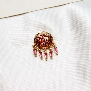 Vue macro d'un pendentif verrou Ruyi doré avec caractère Fu rouge et cristaux roses