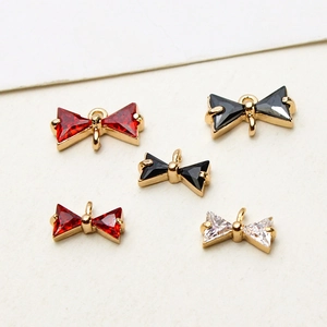 Detail of copper cubic zirconia bow charm and floral pendant for DIY jewelry making