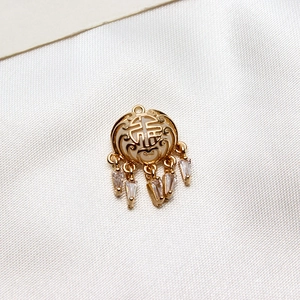 Détail macro d'un pendentif doré ajouré avec caractère Fu et glands en zircon sur soie