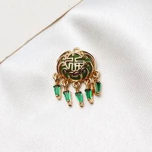 Macro d'un pendentif verrou Ruyi doré avec signe Fu et pierres vertes sur fond de soie