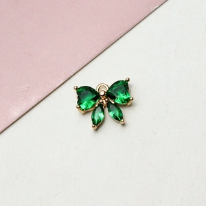 Detailed view of butterfly pendant with emerald green zircons on gold-plated base