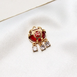Détail d'un pendentif verrou Fu doré avec pierre rouge et accents en zircon