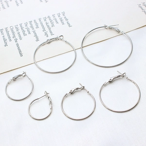 Three pairs of classic silver hoop earrings in different sizes on minimalist white fabric