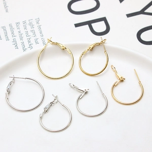 Close-up of assorted gold and silver hoop earrings in various sizes on a white plate