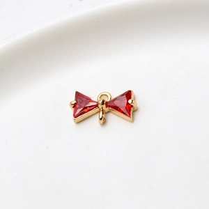 Macro shot of gold-plated bow charm with red zircon stones and dual hanging loops