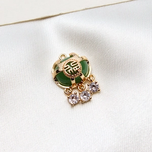Détail d'un pendentif verrou Fu plaqué or avec pierre verte et zircons brillants