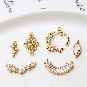 Pendentifs géométriques dorés avec zircons pour bijoux présentés sur une assiette blanche