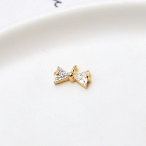 Macro shot of gold bow pendant featuring triangle-cut cubic zirconia and top hanging ring