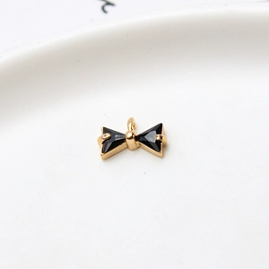Macro detail of gold bow charm with black triangular zircon stones for jewelry making
