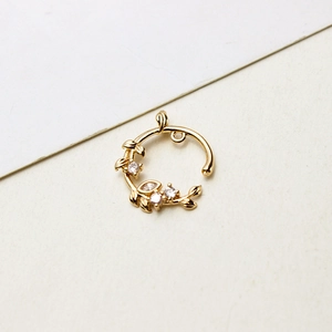 Détail macro d'un pendentif en forme de couronne dorée avec feuilles en zircon et incrustations