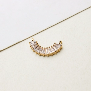 Détail macro d'un connecteur demi-lune doré en zircone avec deux anneaux pour bijoux