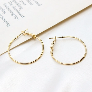 Detail of gold-plated circular hoop earrings with leverback clasp on a silk cloth