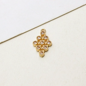 Détail d'un pendentif géométrique doré orné de zircons sertis et d'un anneau de suspension