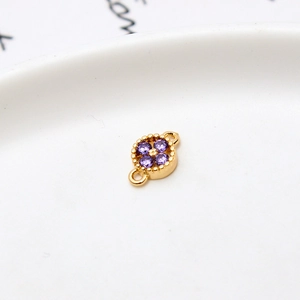 Macro shot of gold-plated flower charm with purple cubic zirconia and dual loops