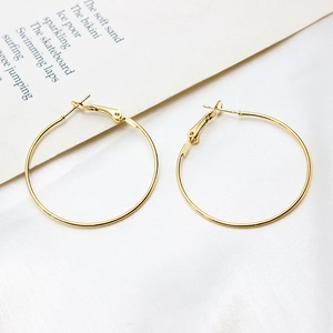 Detailed shot of polished gold-plated geometric hoop earrings with lever-back closure