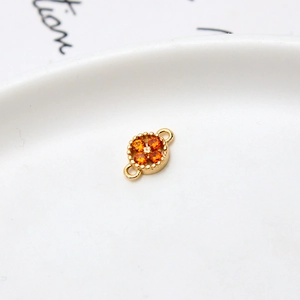 Macro shot of gold floral connector with orange zircons and dual loops for DIY jewelry