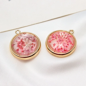 Vue macro détaillée de pendentifs ronds plaqués or avec de vraies fleurs séchées roses