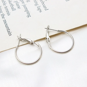 Close-up of polished silver leverback hoop earrings on a minimalist textured background