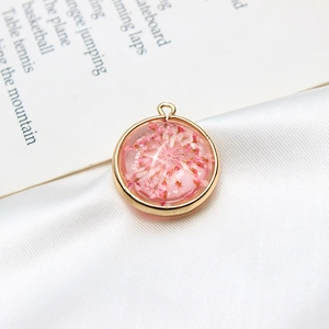 Gros plan détaillé d'un pendentif rond doré avec de véritables fleurs séchées roses