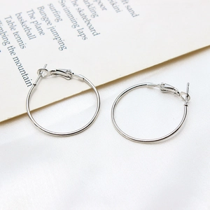 Macro view of silver circular hoop earrings with hinged closure on silk fabric