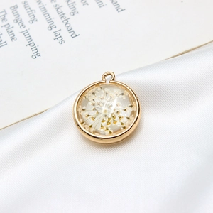 Vue macro d'un pendentif rond doré avec fleur séchée blanche dans de la résine