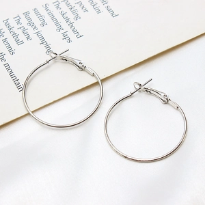 Detail view of silver-plated large hoop earrings on elegant silk fabric background