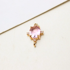 Detail eines rosa ovalen Zirkonia-Anhängers mit Goldbasis und kleinen Steinen